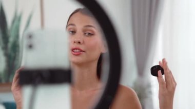 Sosyal medya için güzellik ve kozmetik video içeriği hazırlayan genç bir kadın. Güzellik blogcusu kameraya gülümserken seyircilere ve takipçilere güzellik bakımını gösteriyor. Düzenle