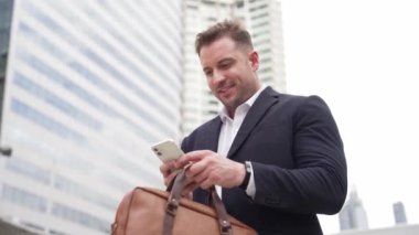 Kafkasyalı iş adamı şehir merkezinde dururken cep telefonlarını kontrol ediyor ve pazarlama ekibinden satış raporlarını inceliyor. Yetenekli bir yönetici cep telefonu üzerinde çalışıyor ve veri analizine bakıyor. Urbane.