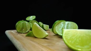 Yakın plan, canlı bir dilim taze kireç kırsal bir ahşap kesme tahtasının üzerinde duruyor. Tazelik ve canlılık yayıyor. Kesme tahtasına konmuş yeşil limon diliminin yarı saydam zarları. Geliştirilebilir.
