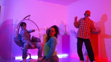 İspanyol hipster renkli kıyafetler giyer ve serbest stil müziğe el sallar. Profesyonel break dansçı neon ışıklarıyla ve modern stüdyo arkadaşlarıyla coşkuyla dans ediyor. Mutluluk.