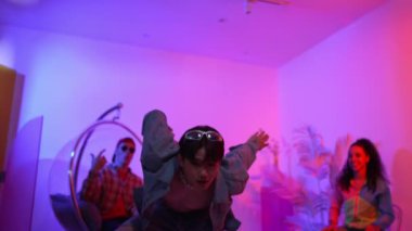 Çok kültürlü bir arkadaş kürsüde otururken Asyalı yetenekli bir dansçı modern müziğe geçiyor. Profesyonel dansçı, hipster takımı tezahürat yaparken ve desteklerken enerjik adımlar atıyor. Mutluluk.