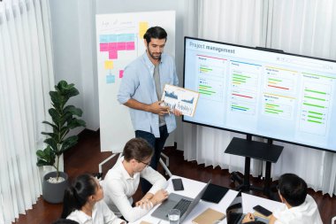 Proje yöneticisi monitörde proje yönetimi yazılım görüntülemesi, proje görevinin ilerlemesini izlemek ve toplantı masasında program planı yapmak suretiyle ekiple iletişim kurar ve işbirliği yapar. Tedbirli