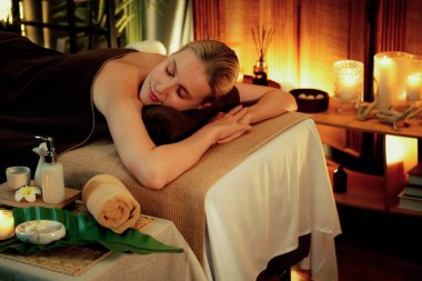 Beyaz kadın müşteri stres önleyici spa masajının keyfini çıkarıyor ve lüks otel ya da otelde sıcak mum ışığında güzellik teniyle eğleniyor. Sessiz.