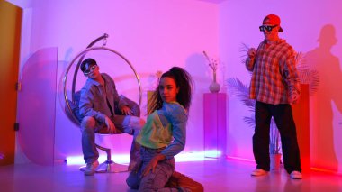 Çekici mutlu dansçı kameraya bakarken zeki kadın neon ışıkla kafiyeli hareket ediyor. Profesyonel İspanyol şarkıcı çeşitli arkadaşlarıyla renkli kıyafetler giyerken break dans yapıyor. Mutluluk.