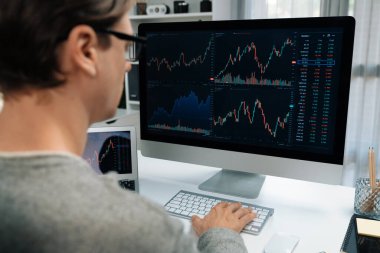 Bilgisayar ve dizüstü bilgisayarı kullanarak, çalışma masasındaki dinamik artırılmış borsa grafiğinin en yüksek kar değerini araştıran bir tüccar, modern ofisteki ekrandaki döviz kuru değerini analiz ediyor. Bireysel.