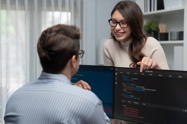 Masada çalışan erkek programcının karşısında duran kadın meslektaşım iki bilgisayar ekranında kodlama web sitesi yazılım sistemi projesini tartışmak için tam yığın veri dizaynı ile karşılaştırıyor. Varsayım.