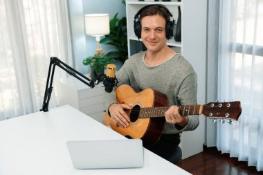 Akıllı şarkıcı görünümlü kamerada sunucu kanalı, şarkı söylerken gitar çalmak, sosyal medya kanalında yayın yapmak, modern stüdyo kaydında video kaydedici olarak kulaklık takmak. Bireysel.