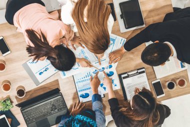 Modern ofisteki iş adamları ve iş kadınlarıyla grup toplantısındaki iş adamlarının en üst düzey görüşü, masada dizüstü bilgisayar, kahve ve belge ile. Kurumsal şirketler uds