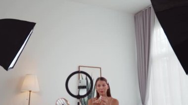 Sosyal medya için güzellik ve kozmetik video içeriği hazırlayan genç bir kadın. Güzellik blogcusu kameraya gülümserken seyircilere ve takipçilere güzellik bakımını gösteriyor. Düzenle