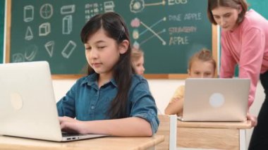 Akıllı Asyalı kız, mühendislik komut yazarken kameraya bakıyor. Çok kültürlü bir öğrenci yapay zekayı öğrenirken öğretmenler sistemi öğretiyor ya da STEM sınıfında sınıfları kontrol ediyor. Pedagoji.