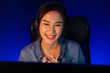 Sunucu kanalı Asyalı etkileyicisi canlı yayında konuşuyor. Sosyal medyada kulaklık takıyor, bilgisayar kaydı yapıyor, dinleyicileri selamlıyor ve Neon Modern Stüdyoları 'nda online olarak koçluk yapıyor. Taktik.