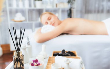 Aromaterapi masajı gündüz atmosferinde ya da spa salonunda bulanık bir kadına odak dekor ve spa aksesuarları kurarak tatil köyünde ya da otel arka planında keyifli aroma spa masajı yapan bir masaj. Sessiz.