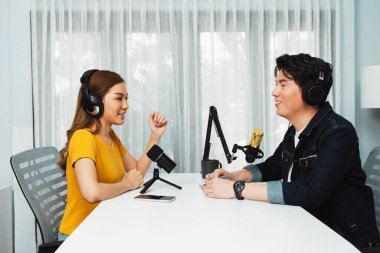 Gülümseyen radyo etkili sunucusu kulaklık takıyor kadın konuşmacı ile röportaj yapıyor sosyal medya internet sitesinden dinleyicilere bilgi paylaşıyor stüdyo kaydında sabah canlı yayın kanalı. İnfobahn.