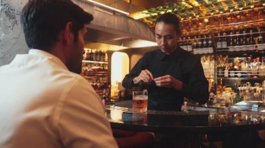 Barmen portakal kabuğu sıkar, cam kokteyl viskisinin üzerinden kokar, buz kalıbının tepesine eski moda kokar. Kulüpteki lüks gişe barında VIP müşteriye özel sunum yapar. Vinosity.