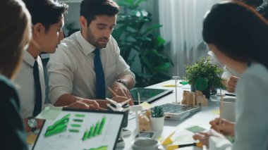 Profesyonel akıllı iş adamları, temiz enerji ve sürdürülebilir yatırımı rüzgar değirmeniyle toplantı masasında kullanma, çevre grafiği ve ahşap ev modeli ile belgelendirme konusunda tartışıyorlar. Hizalama.