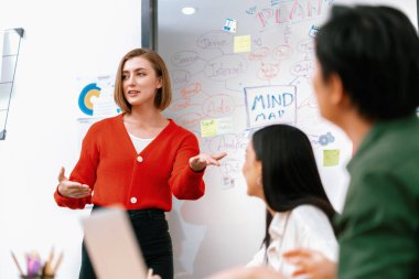 Kafkasyalı genç bir iş kadını, pazarlama stratejisini zihin haritası kullanarak sunuyor, soruları kendinden emin bir şekilde cevaplarken grafiğini çiziyor. Takım çalışması, beyin fırtınası, tartışma konsepti. Tertemiz..