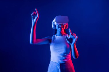 Siberpunk neon ışığı altında duran zeki kadın metaevrene bağlı VR kulaklık takıyor, gelecekçi siber uzay topluluğu teknolojisi. Zarif bir kadın parmak ucu kullanarak sanal bir obje oluşturur. Halüsinasyon.