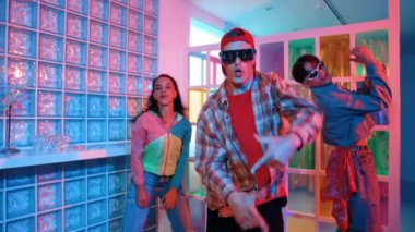 Değişik takımlarla dans ederken süslü gözlük takan yakışıklı hippi serbest stil müzikle mutlulukla dans ediyor. Beyaz hipster kulüpte parlak neon ışıkta sokak dansı yapıyor. Mutluluk.