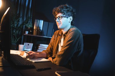 Genç işadamı, Neon Light Modern Ofis 'te yaratıcı bir başlangıç projesi için bilgisayara odaklanıyor. Düşünüyorum da, pazarlama ağı yaratıcıdan pazar kanalı tasarım konseptine çevrimiçi planlama. Toplayıcı.