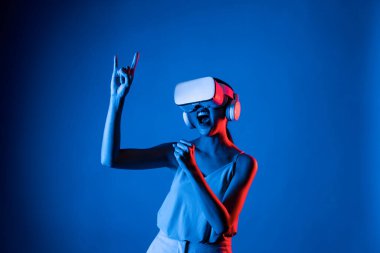 Zeki bir kadın, metaevreni birbirine bağlayan VR kulaklık takan neon ışıklarla çevrili duruyor. Gelecekteki siber uzay topluluğu teknolojisi. Zarif bir kadın dans etmekten, dans etmekten ve şarkı söylemekten hoşlanır. Halüsinasyon.