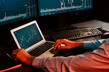 Dizüstü bilgisayarda araştırma yapan genç yatırımcı hisse senedi tüccarı, güncel pazar grafiğinin dinamik döviz kuru ekranlarıyla gerçek zamanlı olarak neon ışığı modern ofisinde finansal verileri analiz ediyor. Toplayıcı.