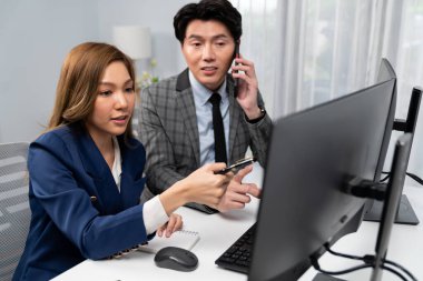 İş ortağıyla cep telefonundan arayan işadamı bilgisayardaki kadın iş arkadaşıyla hisse senedi değer veri tabanını hesaplarken şirket değerini analiz ediyor ya da güncel alım yapıyor. İnfobahn.