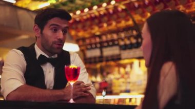 Barmen lüks tezgah barında güzel misafirler için çiçeklerle süslenmiş karışık votka kokteyli servis ediyor. Mükemmel canlı renk sunumu. Atmosfer gece kulübünü ön plana çıkarıyor. Vinosity.