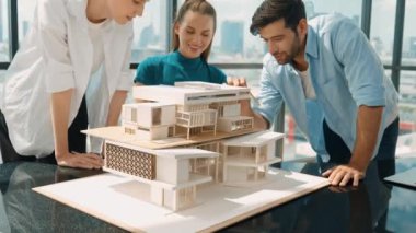 Beyaz proje yöneticisi dizüstü bilgisayar analiz verilerini kullanırken, mimar mühendis ekibi ev modeli inşaatını analiz etmek için birlikte çalışıyor. Bir grup tasarımcı ev tasarımı hakkında konuşuyor. İzleme