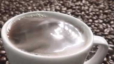 Kahve ya da kahve çekirdekli espresso manzarası. Taze kavrulmuş kahve çekirdeğini yakın çekimde ahşap masanın etrafına bir fincan americano ve aromatik akarsu ve tohum dumanı serpin. Geliştirilebilir.