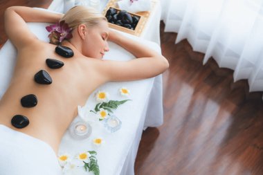 Lüks tatil beldesindeki kaplıca salonunda sıcak taş masajı. Gündüz huzurlu ortam, mutlu kadın müşteri bazalt taşı masajının keyfini çıkarıyor. Sessiz.