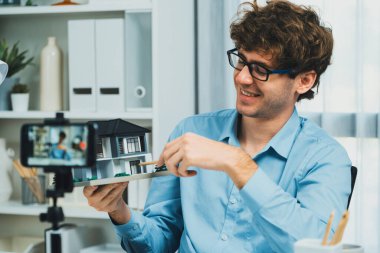 Mimarinin sunucu kanalı ev modelini kullanarak mimarlara akıllı telefon kayıtlarını küçük modelde öğretmek, evdeki sosyal medyada dinleyicilerle iletişim kuran modern ev tasarımı dinleyicilerini açıklamaya işaret ediyor. Toplayıcı.