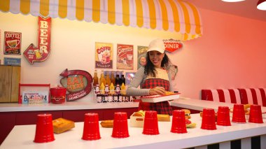 Profesyonel İspanyol restoran işçisi dans ediyor ve yemek barının arkasında duruyor. Kırmızı önlüklü çekici garson kameraya bakarken serbest stil müziğe geçiyor. Çılgın ve komik dans. Mutluluk.