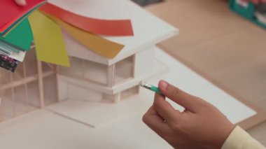 Mimari ekipman kullanarak yavaş çekim ev tasarımcısı bir plan çizerken, iç mimari tasarımcı da müşterilerin talebine göre renk örneklerinden uygun renkler seçiyor. Değiştirilmiş