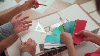 Mimari ekipman kullanarak yavaş çekim ev tasarımcısı bir plan çizerken, iç mimari tasarımcı da müşterilerin talebine göre renk örneklerinden uygun renkler seçiyor. Değiştirilmiş