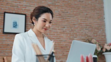 Çalışma masasında internet içeriği için dizüstü bilgisayar kullanan genç bir iş kadını ya da evden çalışan bir sekreter. Canlılık