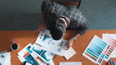 Sıradan giyinen, dizüstü bilgisayara bakan ve fikir paylaşan iş adamlarının en aşağıdan görünüşü. Yapışkan notlar ve kulaklıkla masada çalışan ve renk paletini kontrol eden yöneticinin hava görüntüsü. Sempozyum.