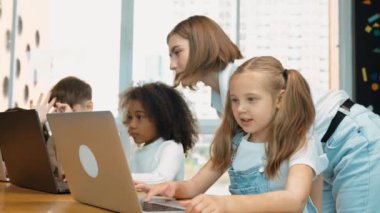 Çok kültürlü bir öğrenci dizüstü bilgisayar kullanarak mühendislik kodları yazarken öğretmen program hakkında açıklama ve öğretim yapıyor. Profesyonel eğitmen BTMM sınıfında programlama sistemini öğrenmeye yardım ediyor. Etkinlik.