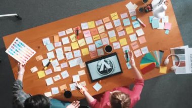 Tablet ekran logosu tasarımı ile toplantı masasında otururken renkli yapışkan notlar üzerine tasarımcı yazma fikrinin üst görünümü. Tasarım yapan ve karar veren profesyonel bir iş kadını. Sempozyum.