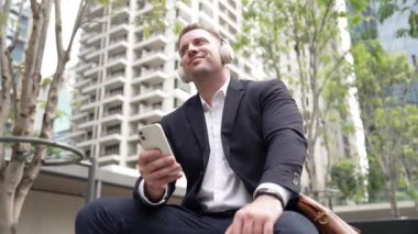 İş adamları, Green City 'deki pazarlama ekibinden gelen satış raporlarını kontrol etmek için telefona bakarken dinlendirici müzik dinlemek için kulaklık takıyor. Happy proje yöneticisi telefon beklerken şarkıya geçiyor. Urbane.