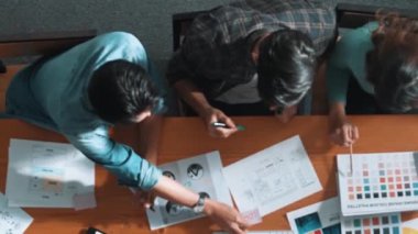 Takım ayakta dikilirken ve yorum yaparken müdürün fikir yazma konusunda üst düzey görüşü. Profesyonel tasarımcı logosu renk paletine bakarken ve renkli kalemle fikri kağıda yazarken. Sempozyum.