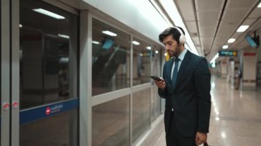 Proje yöneticisi, tren istasyonunda cep telefonu ve arama ekibi tutarken kulaklık takıyor. Zeki iş adamı bulanık bir geçmişi olan treni beklerken rahatlatıcı müzik dinliyor. Sevinçli..