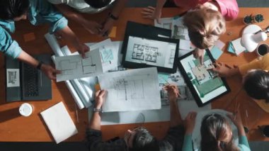 Yetenekli iş adamlarının tablet tutması ve planlara bakması. Masada dizüstü bilgisayarla dururken mimarın tasarım ve planlama bölümünün havadan görüntüsü. Sempozyum.