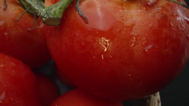 Makrografi, ahşap bir sepete yerleştirilmiş domatesler dramatik bir siyah arka plana karşı sergileniyor. Her yakın çekim domateslerin zengin renklerini ve dokularını yakalar. Geliştirilebilir.