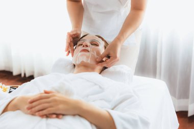 Kaplıca salonunun sakin, modern gündüz atmosferi. Kadın müşteri yüz maskesi takarak kendini yenilemeye çalışıyor. Yüz bakımı ve güzellik kozmetolojisi prosedürü. Sessiz.
