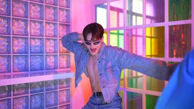 Ortasında dans eden profesyonel mutlu hipster onu alkışlayan çeşitli arkadaşlarıyla dans ediyor. Çekici Asyalı kırığı gece kulübünde neon ışığıyla enerjik adımlar atıyor. Mutluluk.