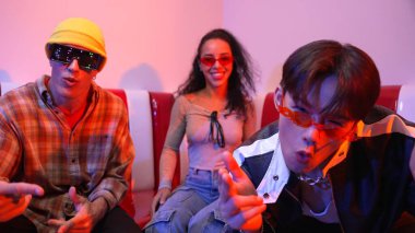 Mutlu kız kameraya bakıyor ve kanepede otururken pop müzik dinliyor. İspanyol kadın serbest stil dans ederken kameraya bakıyor neon ışıkta çeşitli arkadaşlarla dans ediyor. Mutluluk.