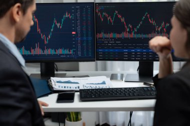 Dinamik borsada döviz kuru yatırımını tartışan iki ticaret simsarı iki bilgisayar ekranında gerçek zamanlı risk grafiği ya da modern ofisteki kar noktasını karşılaştırıyor. Varsayım.