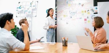 Genç ve güzel lider pazarlama stratejisini sunarken, uzman yatırımcı ve proje yöneticisi de yeni başlayan iş toplantısında iş performansını analiz etmeye çalışıyor. Çok ırklı bir grup. Tertemiz..