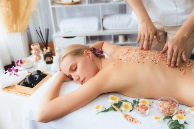 Lüks spa salonlarında sıcak mum ışığında cilt bakımı yaptıran kadın müşteri. Sağlık Spa vücut fırçasında tuz temizleme güzellik tedavisi. Sessiz.