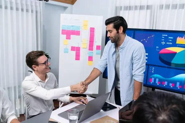 stock image Analyst team leader shake hand with his colleague after successful data analysis meeting using FIntech software power with business intelligence or BI dashboard. Prudent